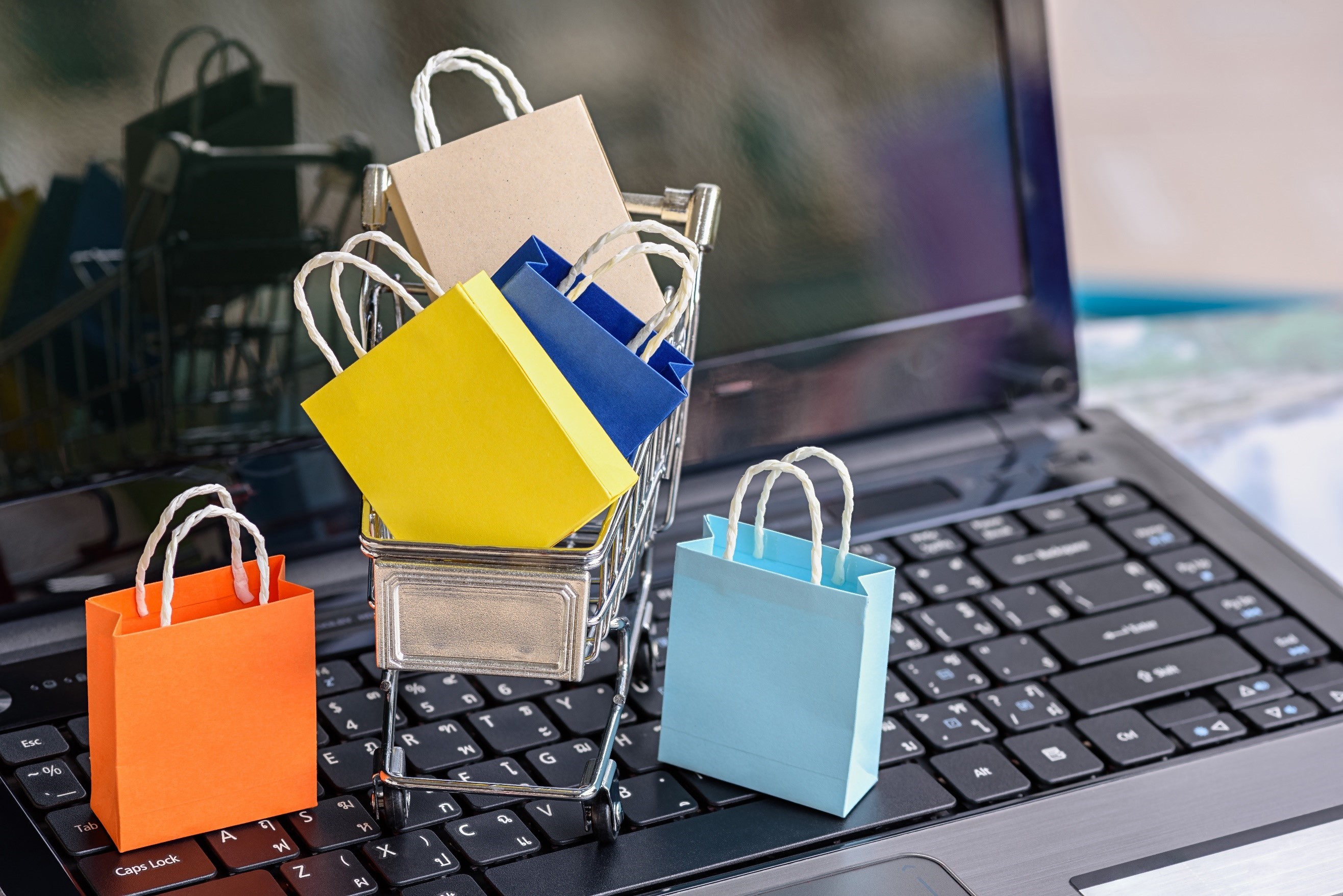 MINI SHOPPING BAGS ON A LAPTOP KEYBOARD REPRESENTING ONLINE SHOPPING