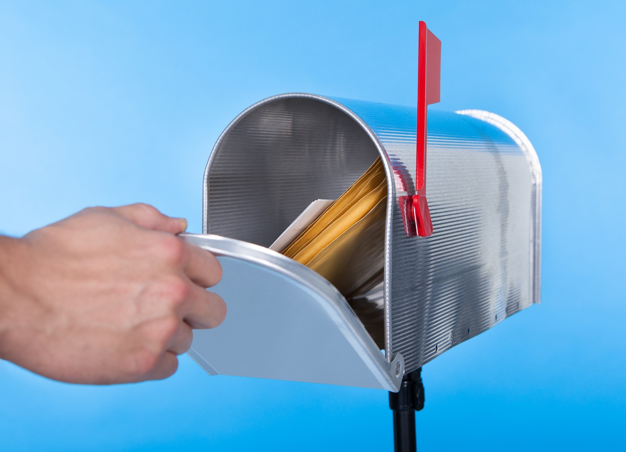 HAND OPENING TO REVEAL MAIL IN A MAILBOX